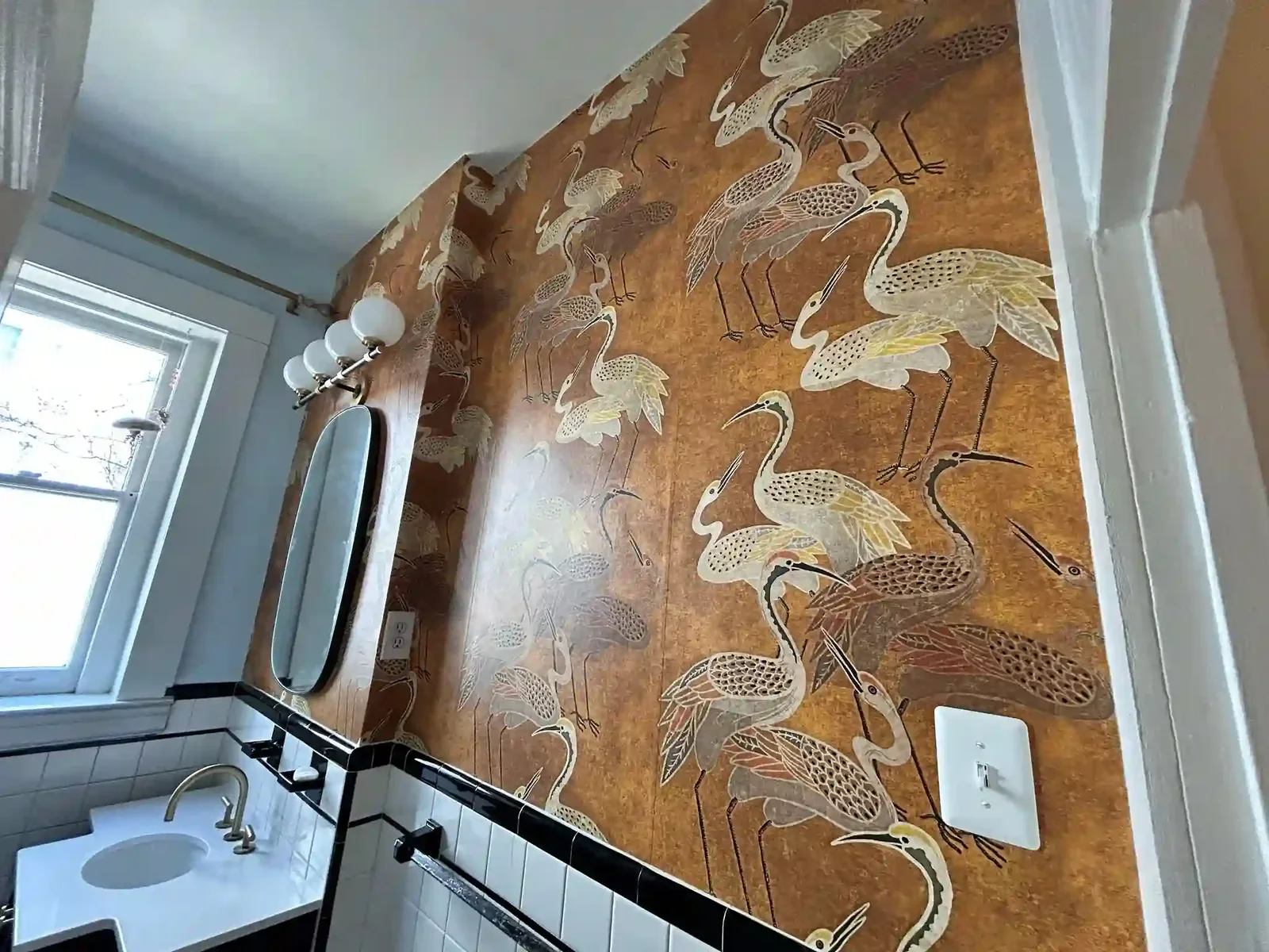 A warm ochre wallcovering patterned with large white cranes above a sink and counter