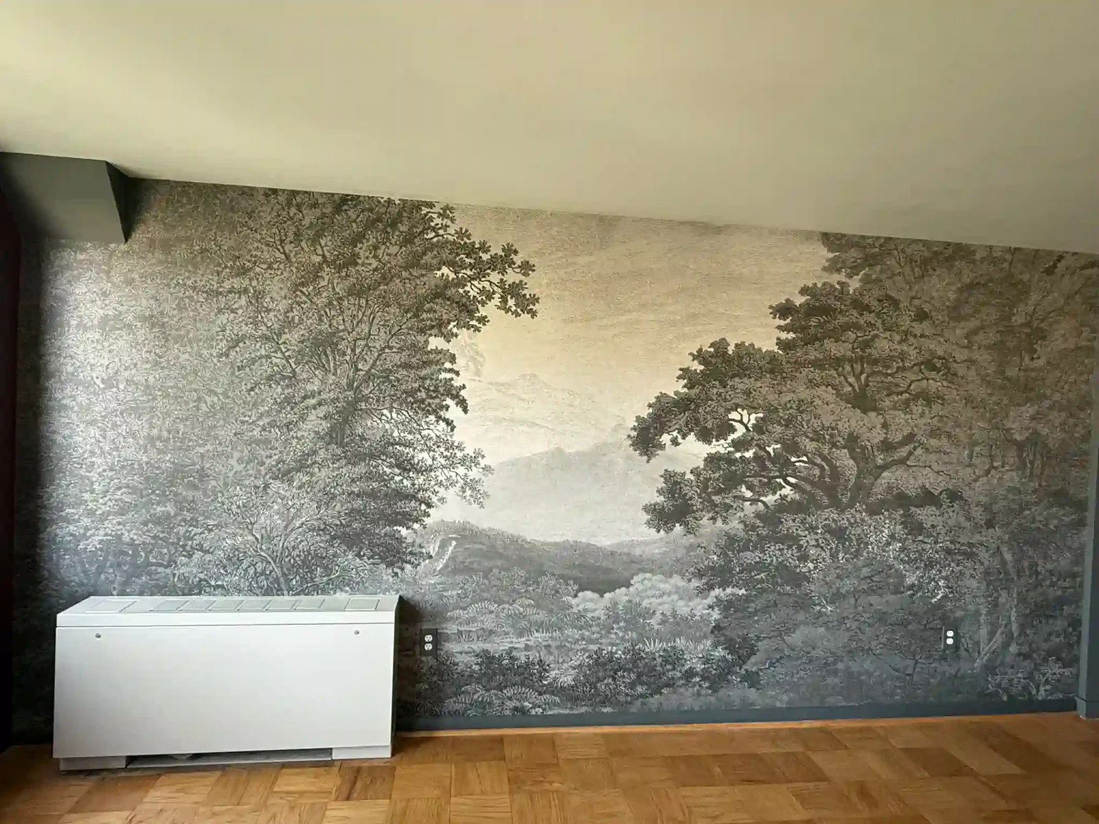 A wall mural depicting trees behind a low white cabinet in a living room