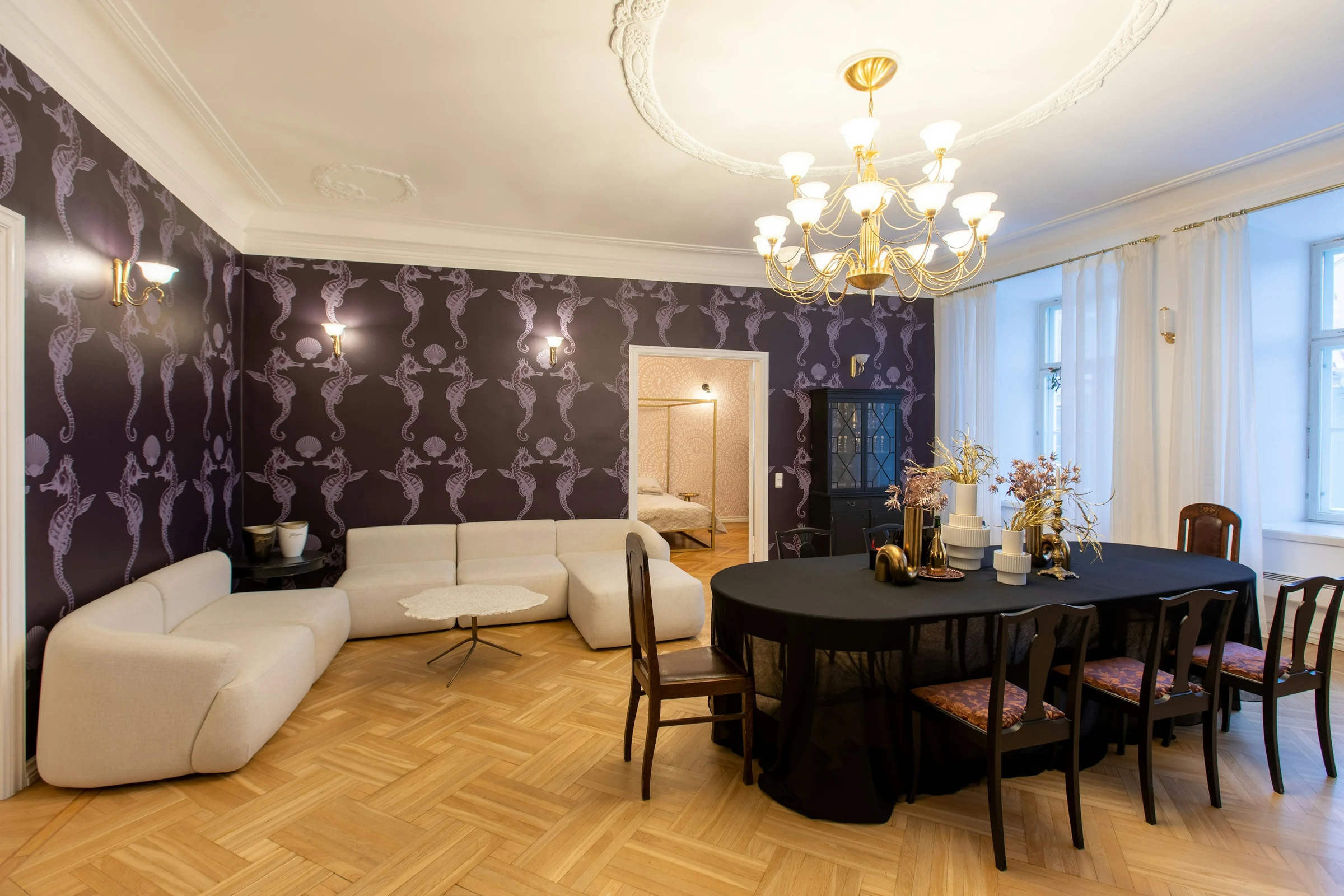 A dark seahorse-patterned wallpaper wall behind a white sofa and dining area
