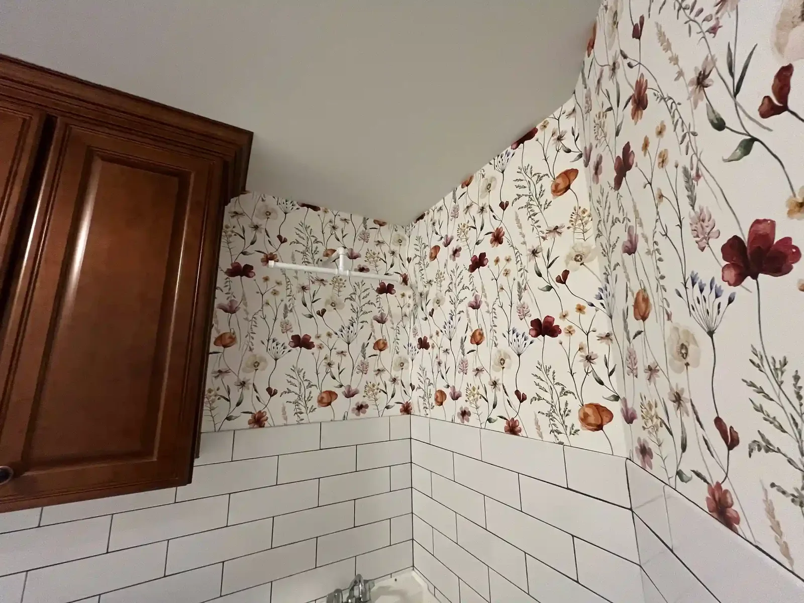 A patterned floral wallcovering meeting painted door trim and a tile wainscot